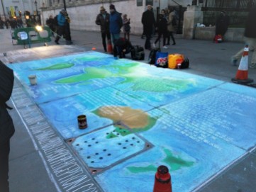 In this photo a chalk artist is working on a world map on the sidewalk in front of the National Gallery